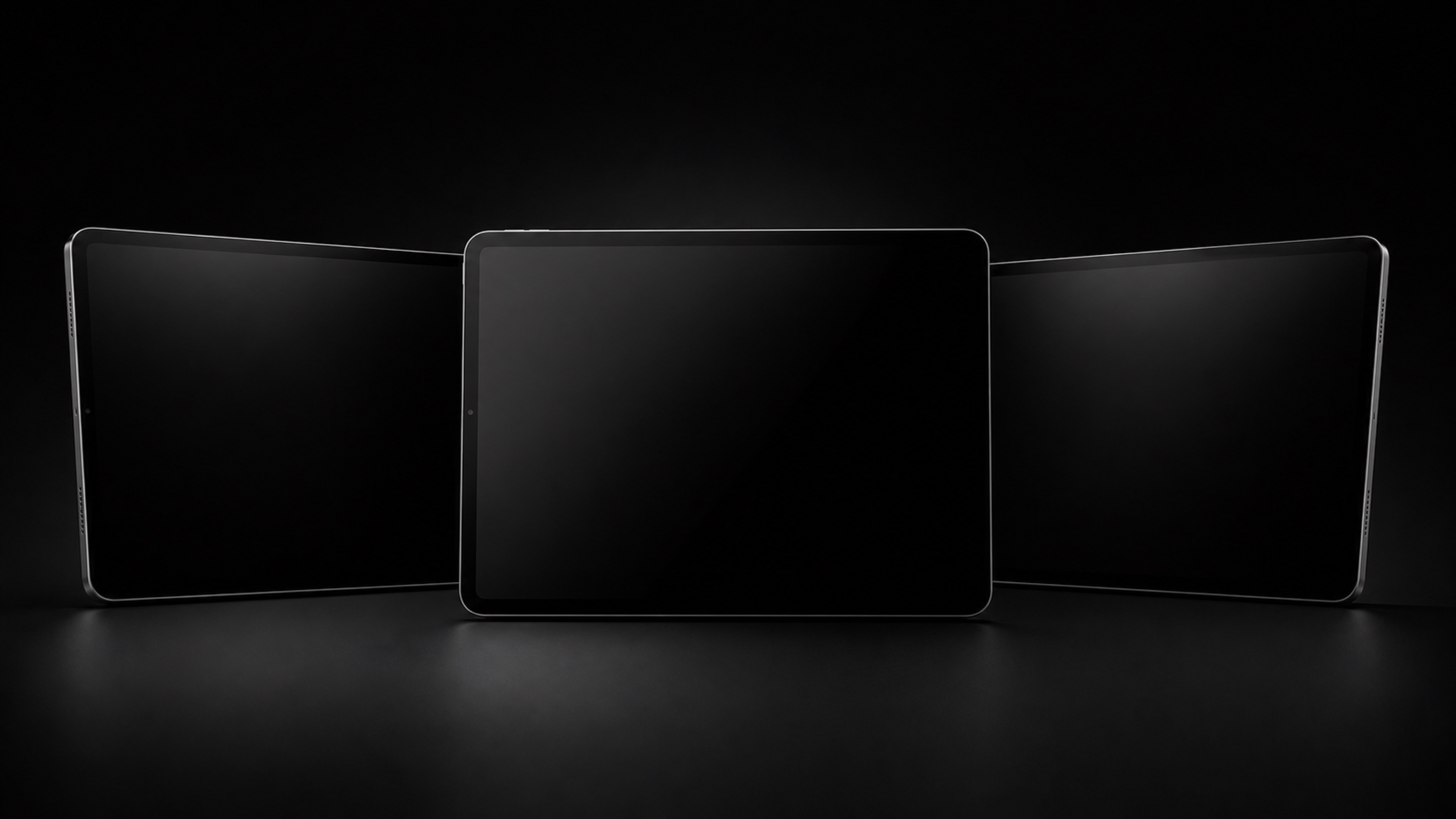 Three blank black tablets on a dark studio background