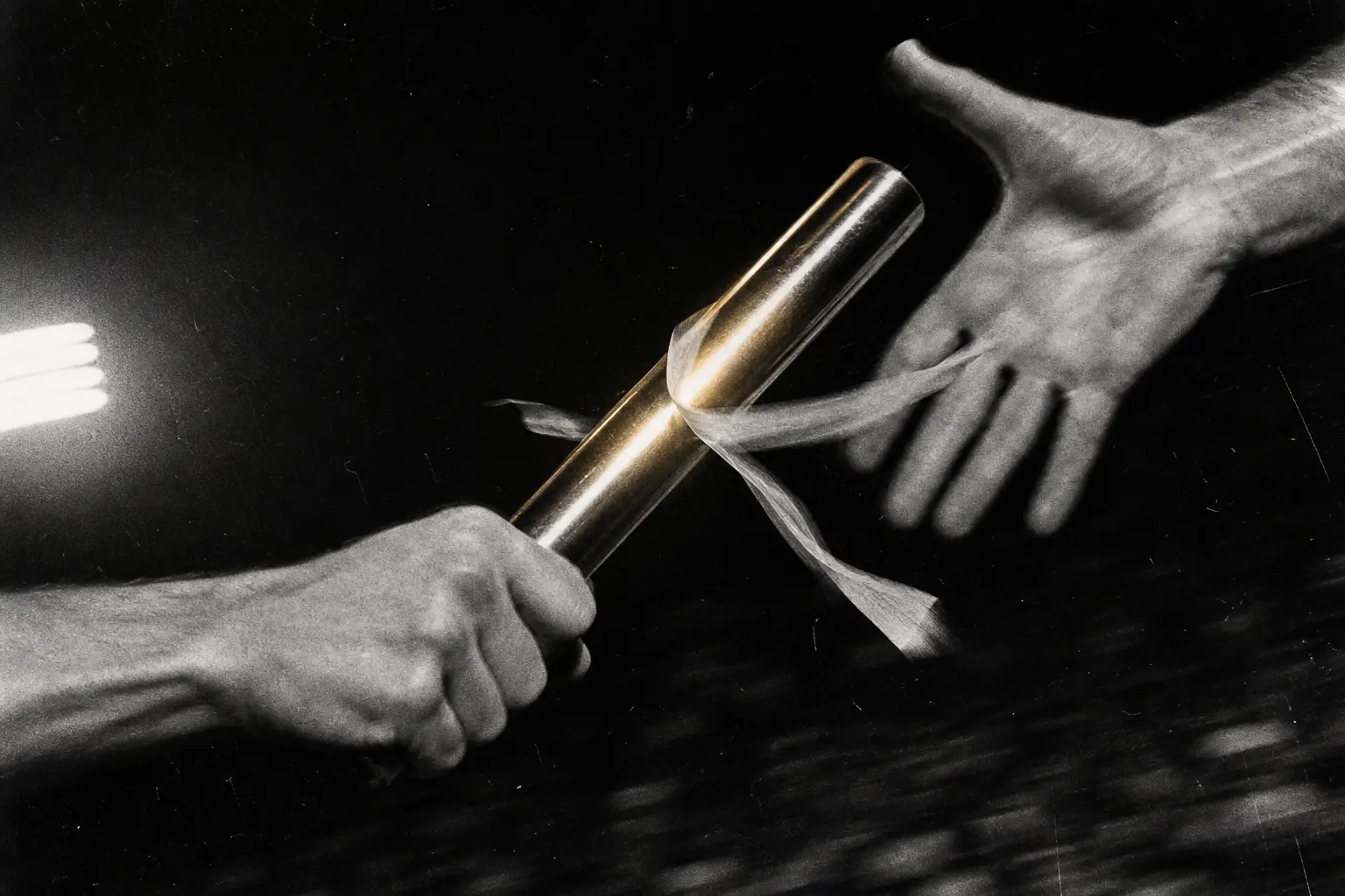 A relay baton suspended between two moving hands